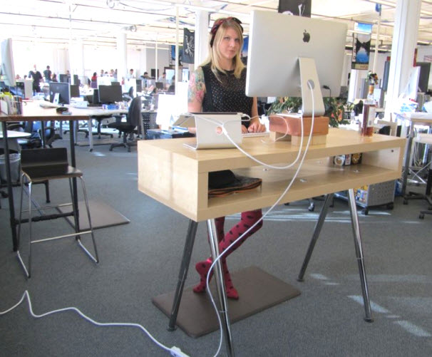 Ergonomie d'une posture debout déficiente au bureau (remarquez le câble d'alimentation sur le sol)